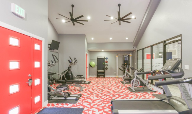 Workout in style in our 24-hour fitness center fitness room with workout equipment and pink door